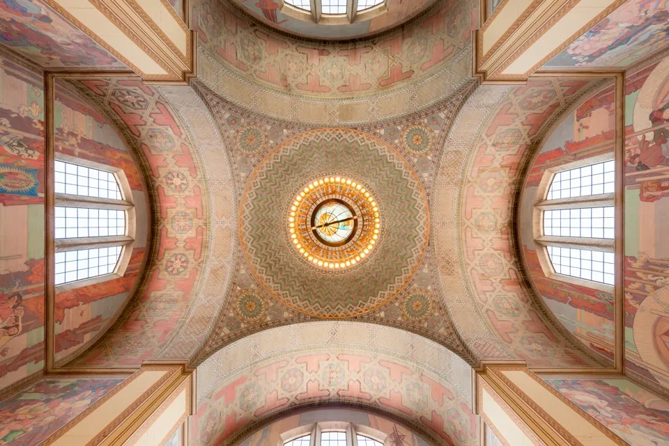 An upward view of the patterned dome and surrounding murals inside Los Angeles Central Library.